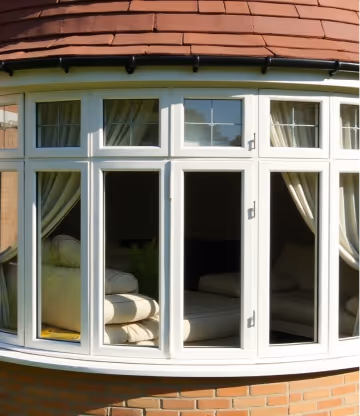  A set of white bow and bay windows with dark handles, seen from the interior.